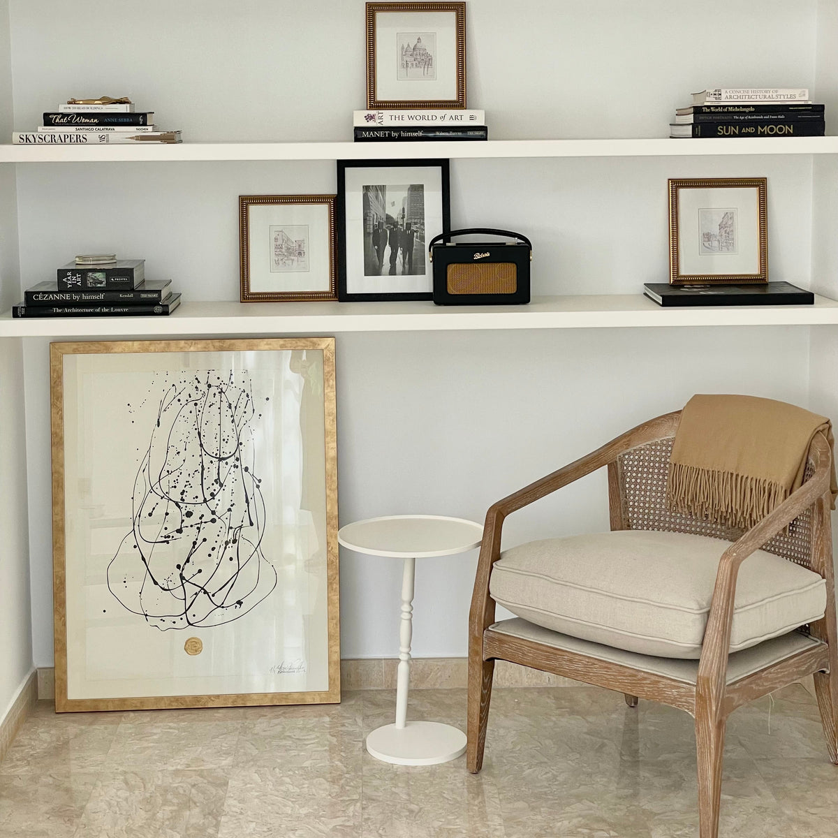 Mesa auxiliar Gorga junto a sillón de comedor, al lado de un cuadro bajo una estantería