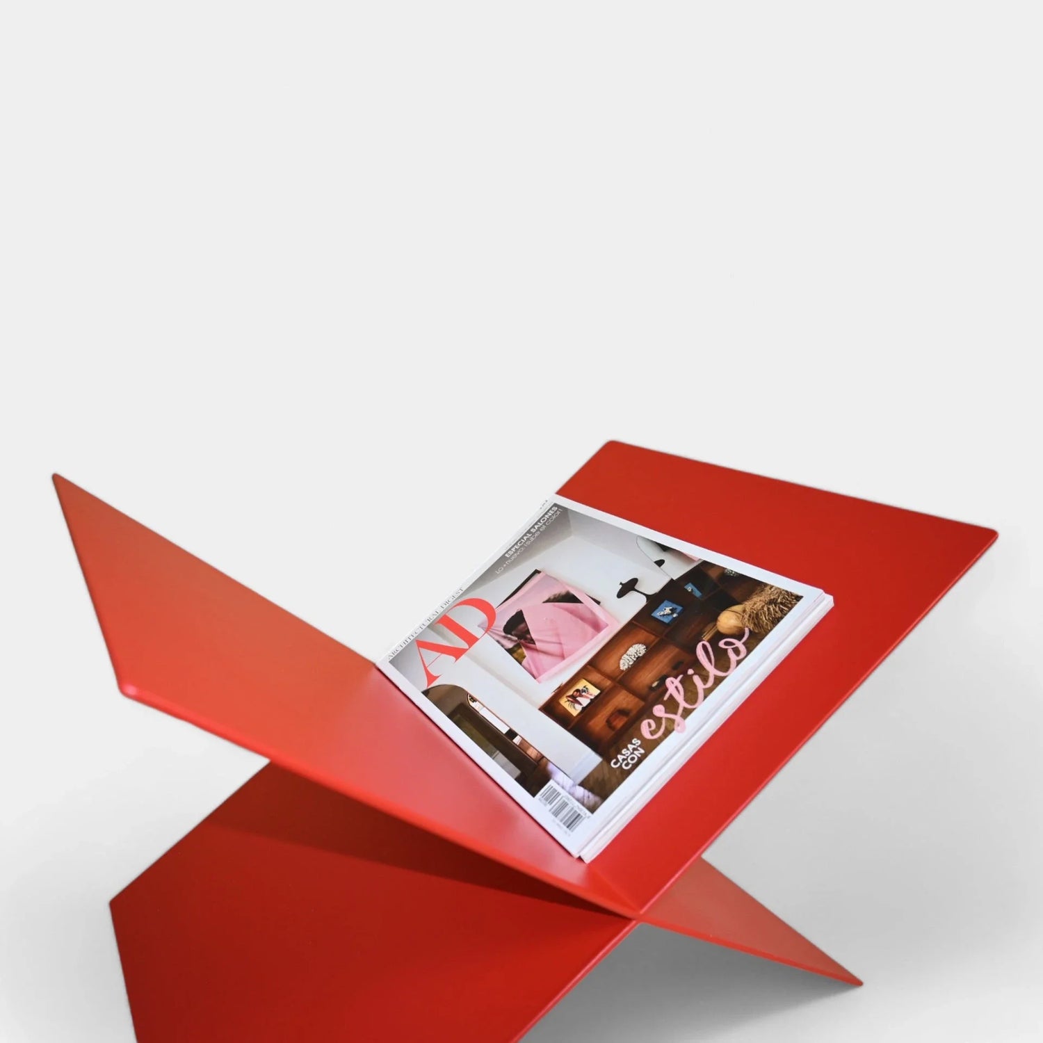 Revistero Culla lacado en rojo texturado, mostrando una revista de decoración