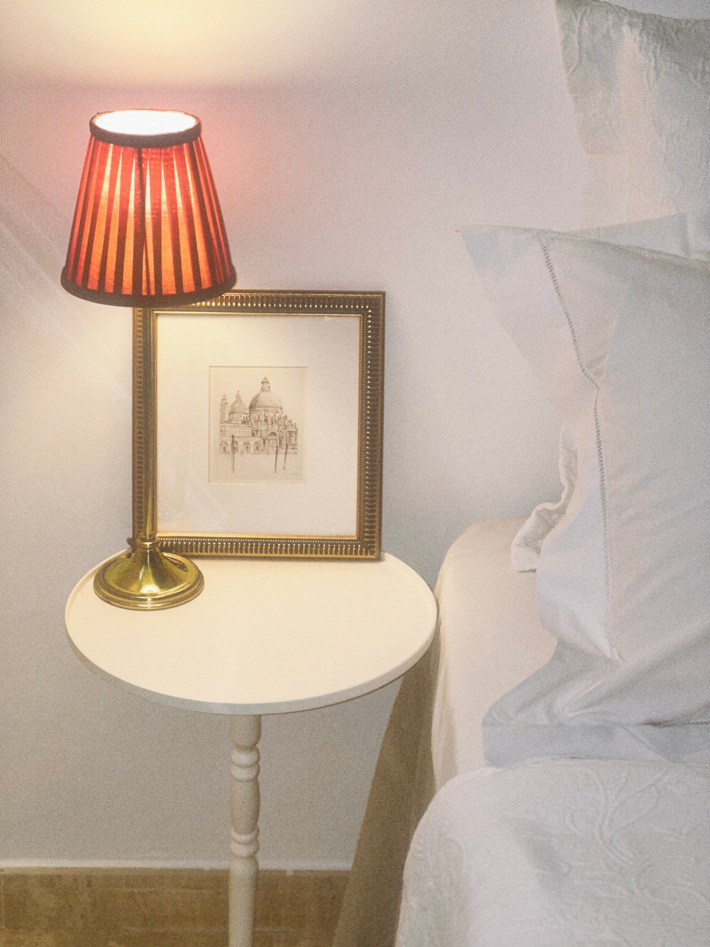 Mesa auxiliar Gorga de cerca con lámpara encima junto a una cama 