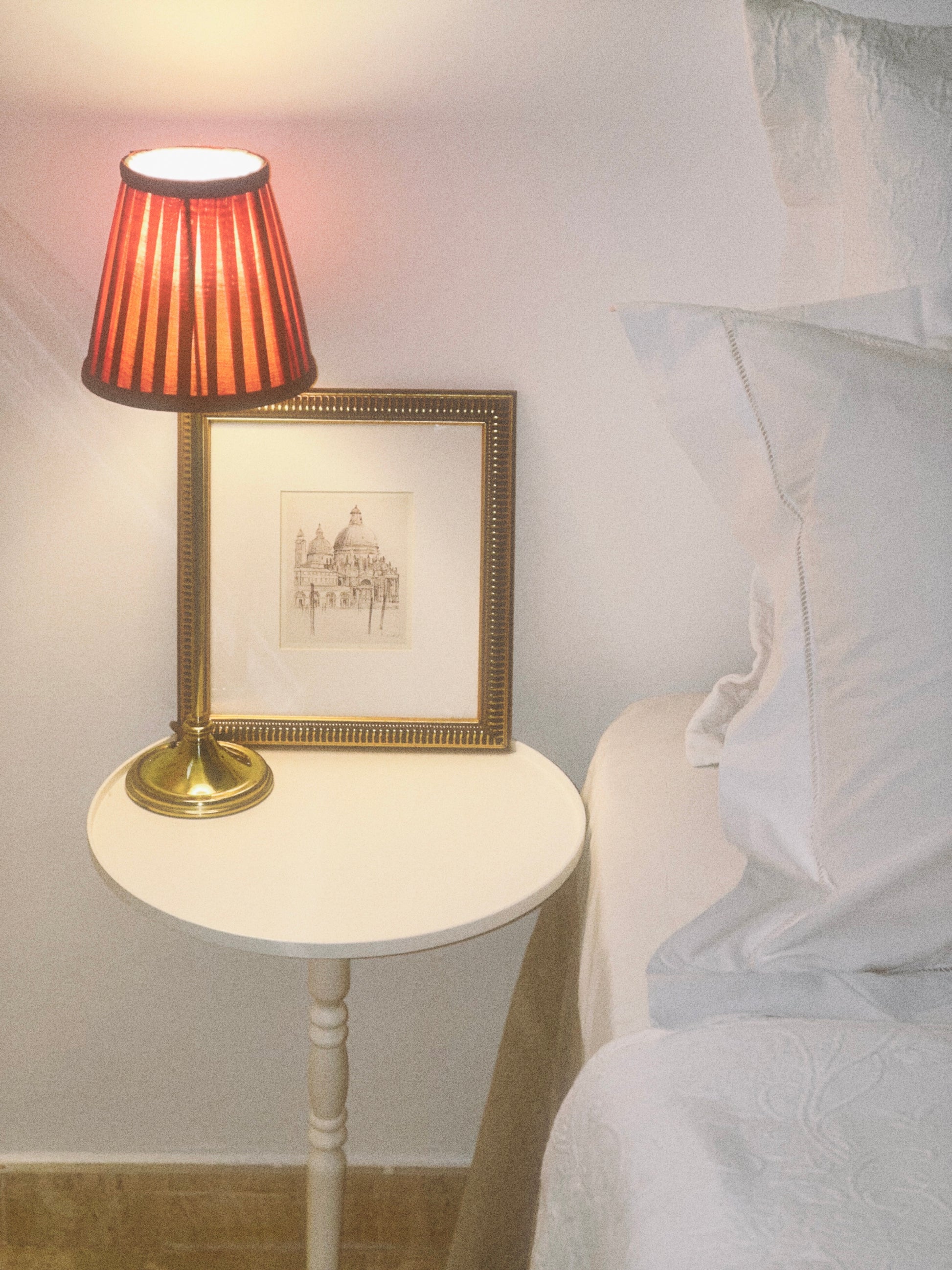 Mesa auxiliar Gorga de cerca con lámpara encima junto a una cama 